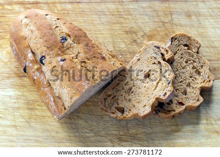 Mediterranean sun dried tomato and olive bread with a shallow depth of field on a cutting board with two sliced pieces and crumbs
