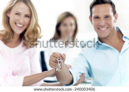 Happy couple holding keys with financial adviser on background