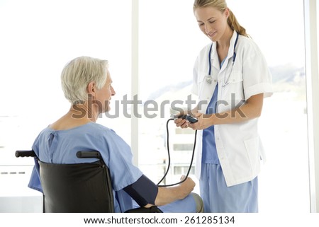 Doctor checking senior patient blood pressure