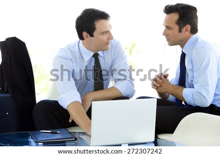 Businessmen working together on laptop in airport lounge