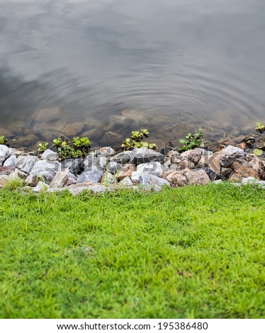 Green grass with stones and water background
