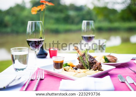 lamb shank and red wine outdoor restaurant table setting