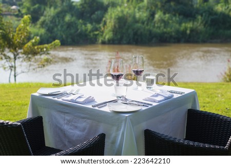 red wine on table set and  green grass background in the garden