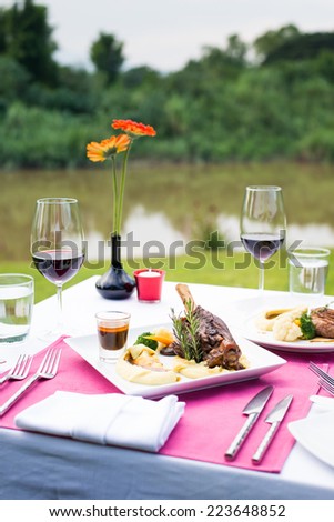 lamb shank and red wine outdoor restaurant table setting