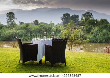 red wine on table set and  green grass background in the garden