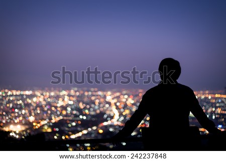 Silhouette of man looking above the city in the night