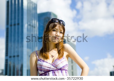 Fashionable Chinese girl in the city. Young female model, pretty Asian girl, fashionable and confident with modern skyscrapers as background.