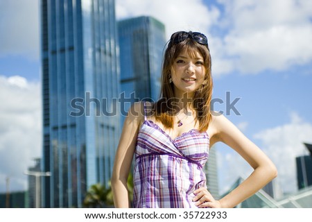 Fashionable Chinese girl in the city. Young female model, pretty Asian girl, fashionable and confident with modern skyscrapers as background.