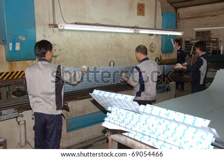 CANTON, CHINA - NOVEMBER 11: One of the biggest manufacturer of auto spray booths and generators in China. Chinese workers use machine to create aluminum profile on November 11, 2010 in Canton, China.