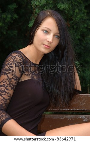 Pretty female model, wearing black skirt. Polish girl sitting at the bank in park.