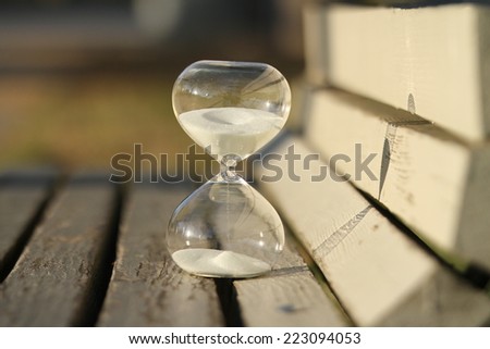sand-glass. Modern hourglass on a bench in a park. symbol of time. countdown.