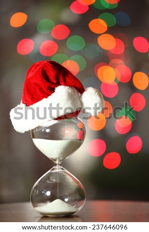 Christmas countdown. Modern Hourglass with space for text -- sand trickling through the bulbs of a crystal sand glass. Christmas light as back ground.