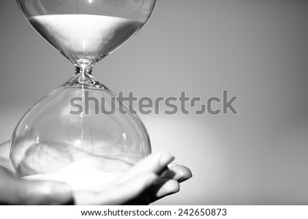 Modern Hourglass -- sand trickling through the bulbs of a crystal sand glass. symbol of time. countdown. Time Management. Hourglass timer concept for business deadline and leadership
