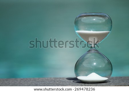 Modern Hourglass -- sand trickling through the bulbs of a crystal sand glass. every second counts. symbol of time. summer countdown.
