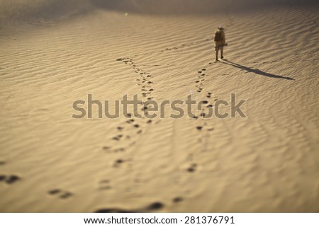 Foot prints and a explorer in the sand in Blur style. Tilt–shift photography.