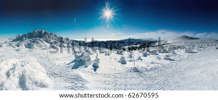 A winter panorama with sunshine, snow, and blue sky.