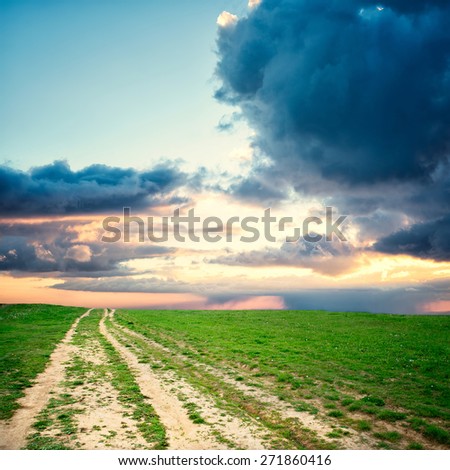 Nature design. Field road in pure nature with blue sky and storm clouds