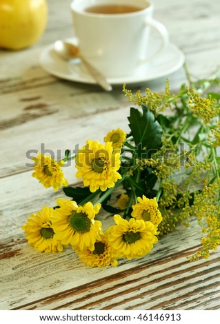 yellow spring flowers and cup of tea on old wooden