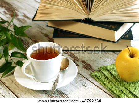 cup of tea, books and apple on wooden