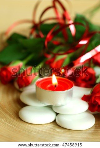 spa composition of candle, stones and roses
