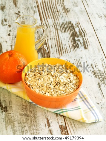 oats in bowl, orange and juice on wooden