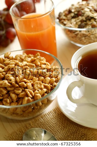 muesli in glass bowl, cup of tea and juice in a glass