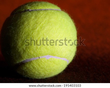 Tennis ball on the orange surface, closeup shot, useful for various, tennis,recreation and sport themes