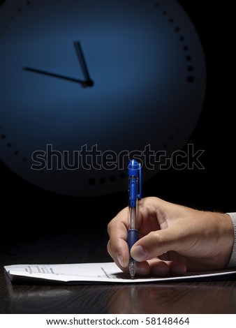 man doing written test with the clock in the background, low key, useful for job application.education and other testing related themes