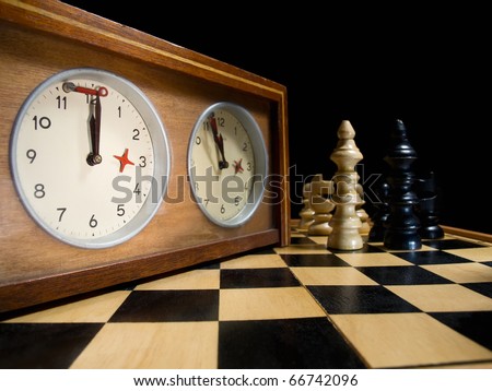 old chess clock on the chessboard with figures ,flag in position which indicates  running out of time