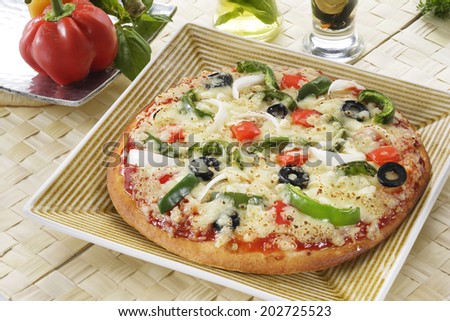 Supreme Pizza in a serving plate with vegetables around.