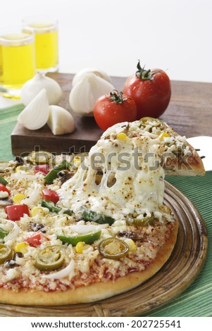 Pizza with lifted slice surrounded by vegetables