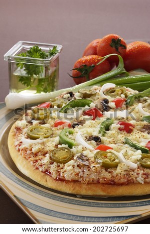 Supreme Pizza in a serving plate with vegetables around.