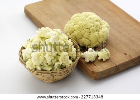 Raw Cut cauliflower in cane container along with chopping board