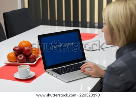 Blonde woman having a system error message on the screen of a laptop.