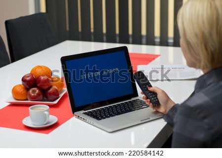 Blonde woman dialing a phone while having a system error message on the screen of a laptop.