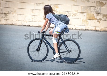 Brunette girl riding a bicycle around the city on a sunny day