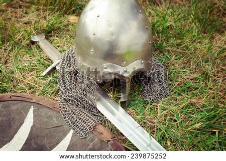Helmet, sword and shield medieval warrior on the grass
