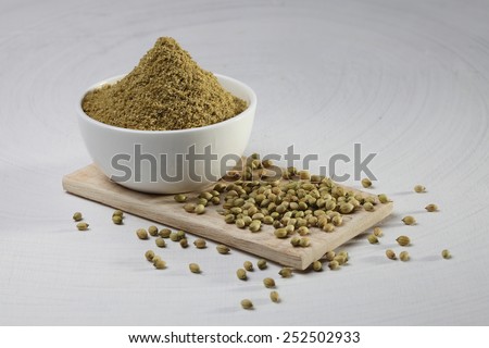 coriander powder and seeds on a wooden base