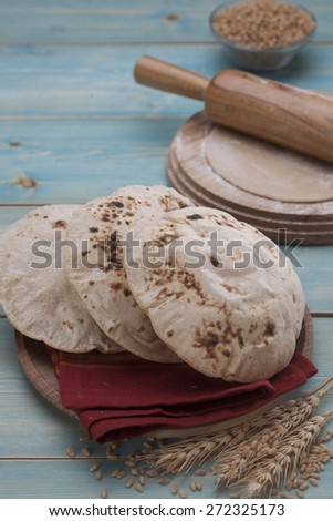 Indian bread in a wooden plate with raw material in the background