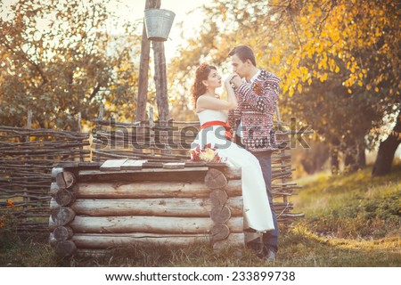 Newlyweds near the wooden well, the groom kisses the bride\'s hand