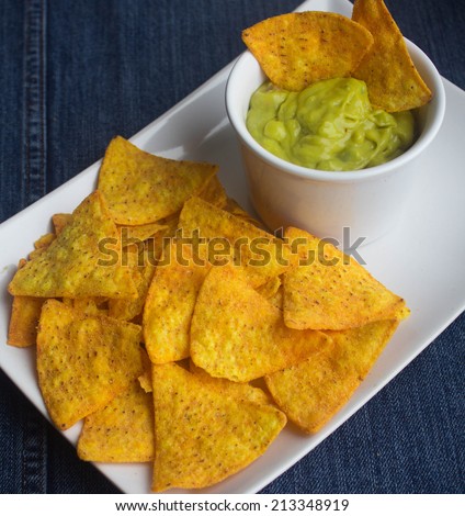 tortilla chips with guacamole on denim background