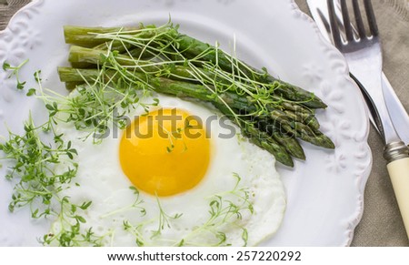 Breakfast of fried eggs, asparagus and watercress salad. Selective focus