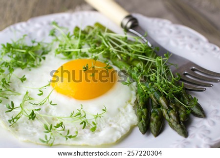 Breakfast of fried eggs, asparagus and watercress salad. Selective focus