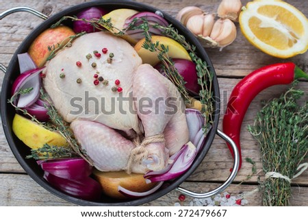 Fresh raw chicken for cooking with red onions, apples and lemon
