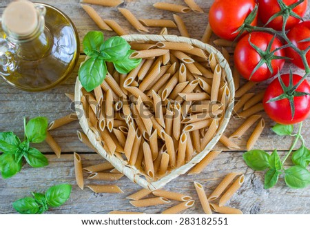 wholemeal pasta. pasta from whole wheat flour, tomatoes and Basil on wooden table