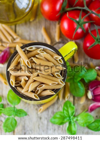 wholemeal pasta. pasta from whole wheat flour, tomatoes and Basil on wooden table