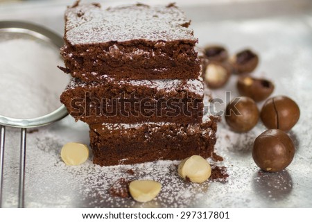Brownie. Chocolate cakes with powdered sugar and macadamia on a metal baking sheet.  American dish.  Selective focus