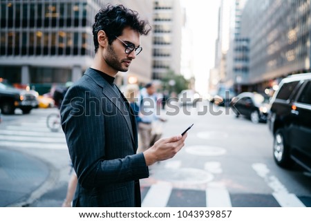 Pensive businessman in suit read incoming notification with money balance on account received on smartphone crossing New York street.Prosperous entrepreneur in formal wear checking mail on telephone
