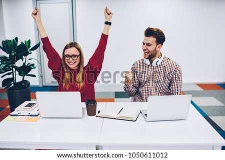 Happy two students rejoicing to win of scientific project in online competition watching live stream on website on laptop.Successful male and female designers celebrating victory sitting at netbooks