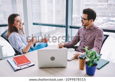 Smiling male and female colleagues joking during communication in office planning strategy for cooperation,prosperous employees making creative decisions for common startup sitting at desktop